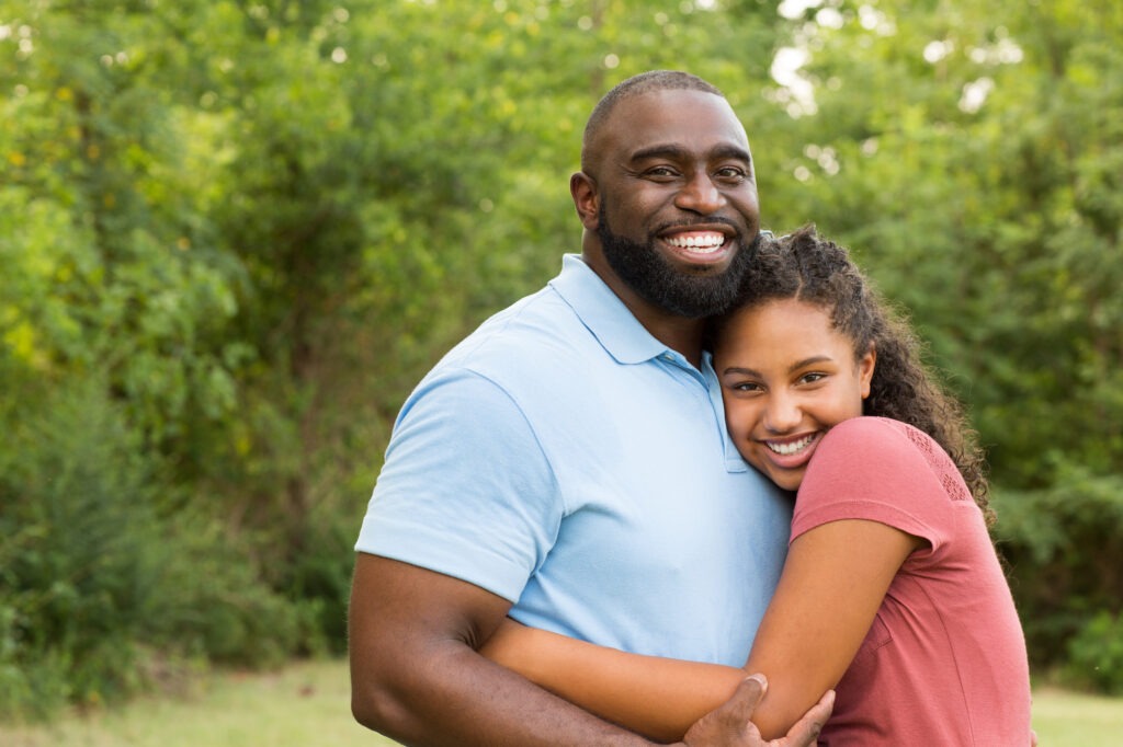 Father and his daughter laughing and playing outside.